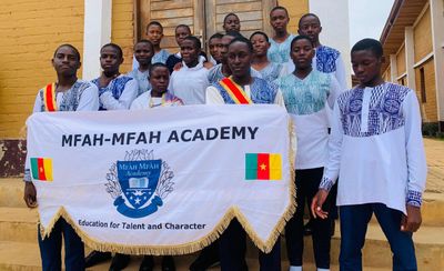 Students holding the Mfàh'Mfàh Academy banner reading Education for Talent and Character, flanked by Cameroon flags