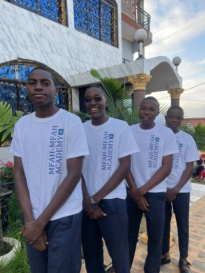 Four Mfàh’Mfàh Academy students smiling in branded school shirts